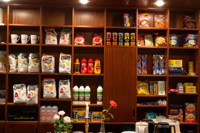 Wide array of packaged groceries neatly arranged on wooden shelves in a store setting. Asortyment sklepu: jak planować, porządkować i uzupełniać ofertę